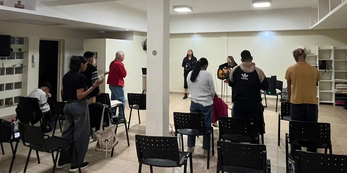 La comunidad de pie durante la alabanza, vista amplia del salón