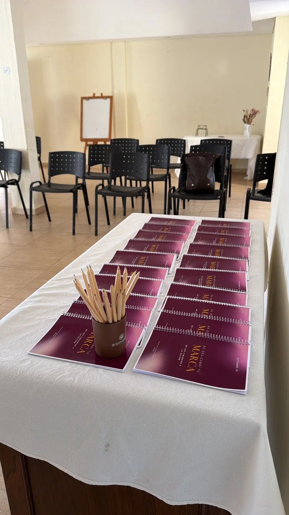 Mesa de recepción con cuadernillos y el salón armado en formato aula